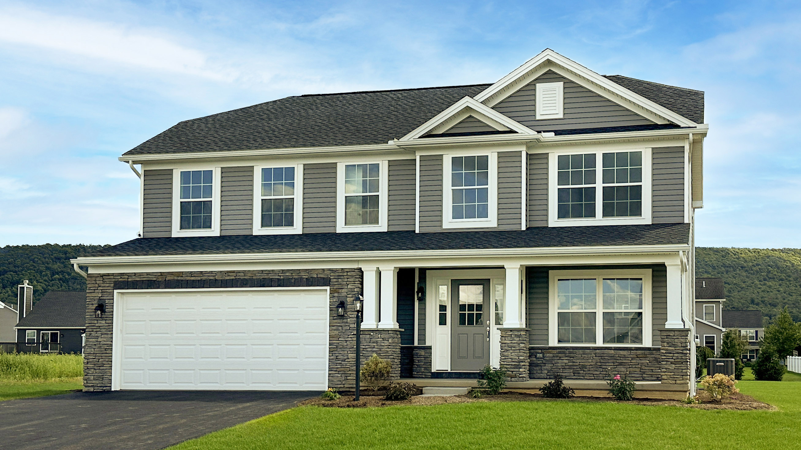 Stage 7 - Welcome Home.jpg: Completed two-story new home exterior with landscaped yard, covered porch, and attached garage, ready for move-in.
