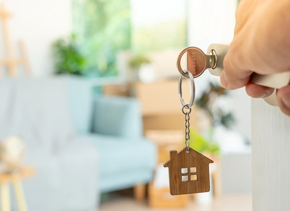 Key with a house keychain inserted inside the key hole of a door being opened.